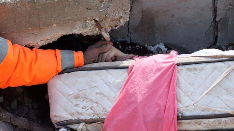 Mesut Hancer holds the hand of his 15-year-old daughter Irmak, who died in the earthquake in Kahramanmaras, close to the quake's epicentre, the day after a 7.8-magnitude earthquake struck the country's southeast, on February 7, 2023. - Rescuers in Turkey and Syria braved frigid weather, aftershocks and collapsing buildings, as they dug for survivors buried by an earthquake that killed more than 5,000 people. Some of the heaviest devastation occurred near the quake's epicentre between Kahramanmaras and Gaziantep, a city of two million where entire blocks now lie in ruins under gathering snow. (Photo by Adem ALTAN / AFP)