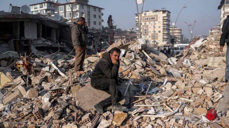 TOPSHOT - A man sits on the rubble of a collapsed building during rescue operations  in Hatay on February 12, 2023, after a 7,8 magnitude earthquake struck the border region of Turkey and Syria earlier in the week. (Photo by BULENT KILIC / AFP)