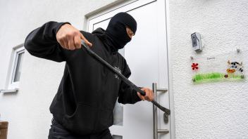 21.11.2022, Thema Einbruchdiebstahl in Wohnhäuser, Symbolbild, Einbrecher versucht mit Brecheisen die Haustüre aufzubrec