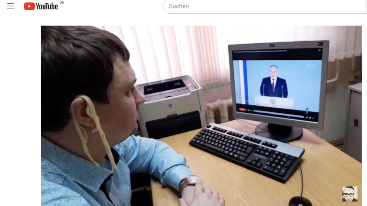 Der kommunistische Regionalpolitiker Michail Abdalkin folgt der Rede von Wladimir Putin mit am Ohr baumelnden Nudeln.