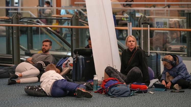 (221220) -- RICHMOND (CANADA), Dec. 20, 2022 -- People wait on the floor at Vancouver International Airport in Richmond