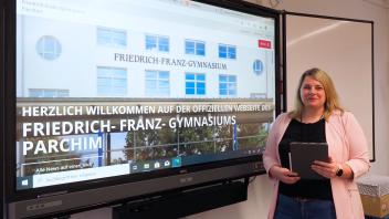 Schulleiterin Franciska Hagen steht mit einem iPad vor einer interaktiven Tafel.