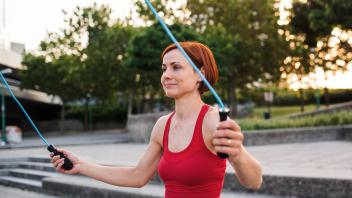 A young woman doing exercise outdoors in city with skipping rope. (halfpoint)