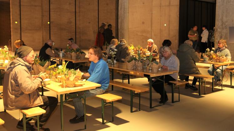 An liebevoll mit Blumen dekorierten Tischen und Bänken in der Tiefgarage essen die Besucher.