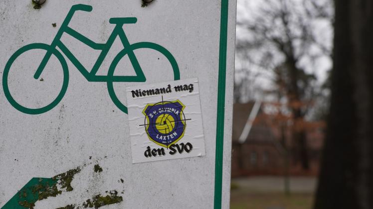 Diese Aufkleber sind an verschiedenen Stellen im Ortsteil Laxten zu finden, vornehmlich an der Josefstraße, aber auch in der Nähe des Sportgeländes. Im Hintergrund ist das Hoekehus zu sehen.