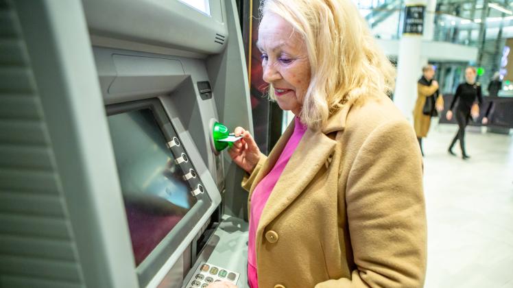 15 February 2023: Woman checking her account balance at an ATM. Pensioner looks sad at an ATM. Symbol picture old age po