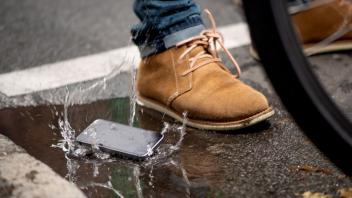 Ein Handy fällt in eine Pfütze