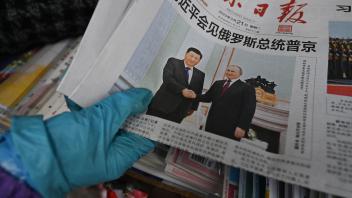 A vendor sorts newspapers featuring a front page photo of Chinese President Xi Jinping meeting with Russian President Vladimir Putin in Moscow, at a news stand in Beijing on March 21, 2023. (Photo by GREG BAKER / AFP)
