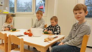 Luisa (4), Mats (6), Momme (3) und Lönne (6) (v.l.) bereiten einen Reissalat aus dem Königinnen- und Ritterkochbuch zu