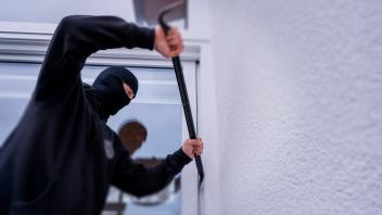 21.11.2022, Thema Einbruchdiebstahl in Wohnhäuser, Symbolbild, Einbrecher versucht durchs Fenster in eine Wohnung zu kom