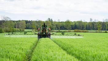 Landwirtschaft - Ackerbau, Pflanzenschutzmaßnahme im jungen Getreidebestand. Landwirt spritzt im Frühjahr seinen Getreid