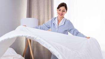 Housekeeper Arranging Bedsheet On Bed ,model released, Symbolfoto PUBLICATIONxINxGERxSUIxAUTxONLY Copyright: xAndreyPop