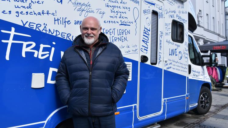 Matthias Kohlstedt steht vor dem blauen Mobil des Blauen Kreuzes