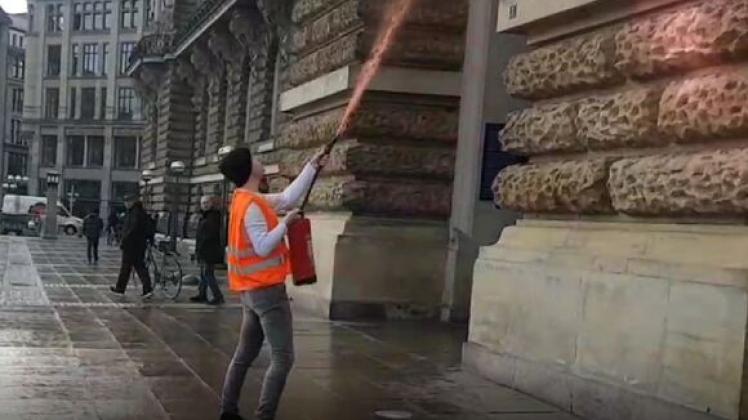 Mit Feuerlöschern sprüht ein Aktivist Farbe an das Eingangsportal.