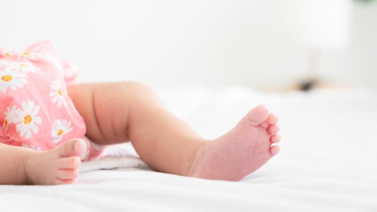 Cute little newborn baby feet on bed at home, Tiny foot of newborn. Soft feet of baby on white blanket at home, Tiny foo
