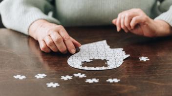cropped view of senior woman playing with puzzles on table