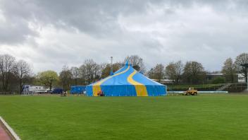 Im Sportpark Illoshöhe in Osnabrück steht am 13. April 2023 ein Zirkuszelt auf dem Rasen. Das Zelt, Fahrzeuge und ein Kabel über die Laufbahn sorgen beim Osnabrücker Turnerbund für Unmut.
