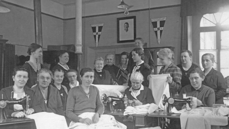 Die NSDAP wirkte bis in nahezu den letzten Winkel der Gesellschaft. Das verdeutlicht auch dieses Foto eines Treffens der Nationalsozialistischen Frauenschaft Lingen 1933. Wimpel, Hakenkreuz und ein Bild vom „Führer“ Adolf Hitler fehlen nicht.