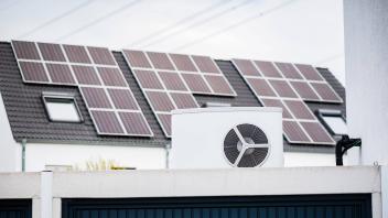 Wärmepumpe auf einem Garagendach eines Neubaugebiets, im Hintergrund sind Solarpanele auf Hausdächern montiert, Monheim 