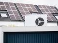 Wärmepumpe auf einem Garagendach eines Neubaugebiets, im Hintergrund sind Solarpanele auf Hausdächern montiert, Monheim 