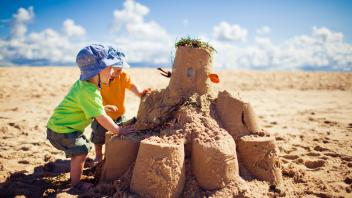 Two little boys building large sandcastle on the beach