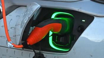 E-Auto am Strassenrand in Muenchen wird geladen,Stecker waehrend dem Ladevorgang an einem E-Auto,E-Autos, Elektroauto,La