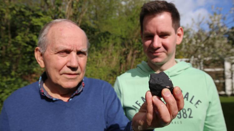 Ein schwarzer Stein, etwa 225 Gramm schwer: Wilfried (links) und Marc Schlabusch aus Elmshorn zeigen ihren Fund. Nun versucht die Familie herauszufinden, ob es sich wirklich um die Überreste eines Meteoriten handelt.