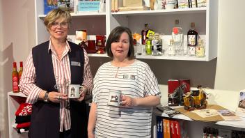 Die Mitarbeiterinnen der Wittenberger Touristinfo Frauke Spiller-Witt (l.) und Sylvia Kieke präsentieren die neuen Tassen, die als Souvenirs neben vielen anderen regionalen Produkten erworben werden können.