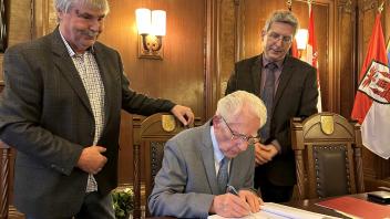 Manfred Wittkowski (M.) trägt sich ins Ehrenbuch der Stadt Wittenberge ein. Beobachtet von Bürgermeister Oliver Hermann (r.) und dem Stadtverordnetenvorsitzenden Karsten Korup. Martin Ferch