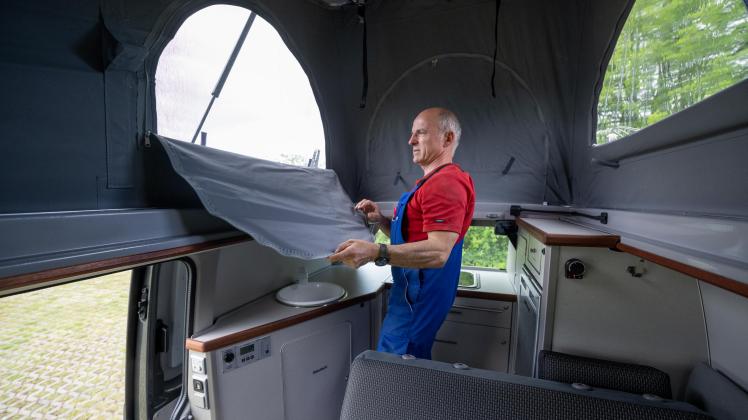 Die Nachfrage auf dem Reisemobile-Markt hält an. Das bekommt einer der wenigen Hersteller von Campingmobilen in Mecklenburg-Vorpommern zu spüren. Östlich von Schwerin entstehen in der Werkstatt von  Wolfram und Andreas Höhne in Leezen seit nunmehr 28 Jahren Campingmobile mit Zweiraumkonzept, Doppelboden und vollwertiger Küche. Das Interesse am individuellem Reisen ist groß und folglich  die Nachfrage beim Campingmobilhersteller. „Wir produzieren Kleinserien auf VW-Basis mit individueller Anpassung“, sagt Andreas Höhne. Weitere Hersteller wie Mercedes sind bereits in der Vorplanung. Jährlich gehen 30 bis 35 Fahrzeuge an Käufer aus dem europäischen Raum. Seit dem Firmenstart sind es 720 Fahrzeuge. Wartezeiten von einem Jahr und mehr  sind programmiert. Dafür gibt Handwerksqualität aus MV. Das sind Fahrzeuge mit Fest- oder Faltdach. Reisemobilfreunde, die noch eine Dusche oder Toilette wünschen, dürfen sich über Konzepte für  kleine Bäume freuen. Das achtköpfige Team von Campingmobil Schwerin fertigt ein Fahrzeug innerhalb von vier Wochen. Wir  haben hinter die Kulissen des Herstellers geschaut. Ein Bildbericht. (Im Foto Andreas Höhne - er erläutert die Funktion des Faltdaches und des Bettes) 16.05.2023 Foto Volker Bohlmann