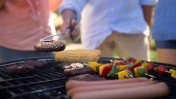 Family grilling patties, vegetables and sausages on the barbecue grill Copyright: xWavebreakmediaMicrox Panthermedia2305