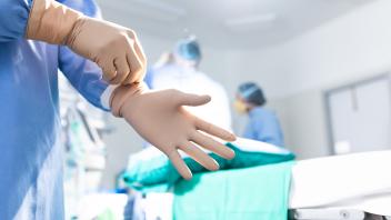 Midsection of surgeon putting on surgical gloves in operating theatre,copy space Midsection of surge