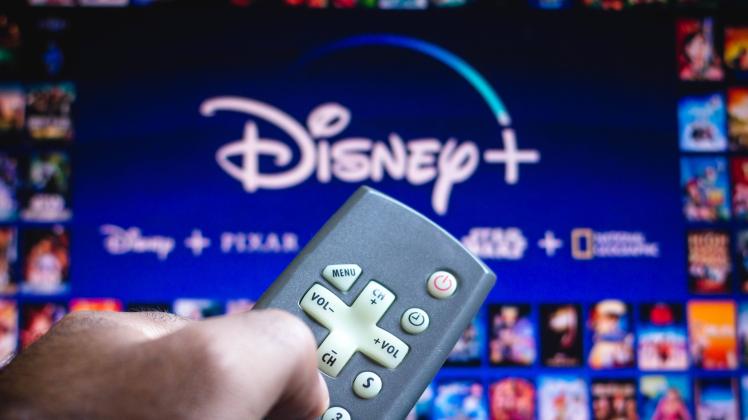 June 3, 2021, Brazil. In this photo illustration a person holds the TV remote control and in the background, the Disney+