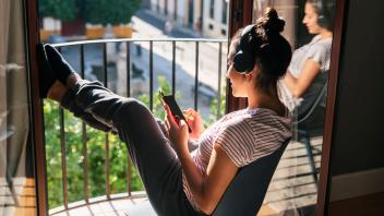 Young woman wearing headphones using mobile phone on chair model released property released, JRVF02017