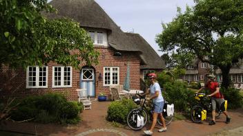 Radfahrer nähern sich einem Ferienhaus auf Amrum. Vermieter und Vermittler von Ferienwohnungen treffen sich im November in Husum zur Messe Domizil.