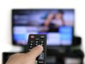 RECORD DATE NOT STATED  Hand holding remote control and a TV screen in the background - binge watching the favourite TV 