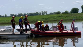 DLRG-Rettungsschwimmer besteigen ihr Boot an der Elbe in Cumlosen. Der Bootsführer bringt sie raus auf den Fluss, damit sie im strömenden Gewässer üben können.