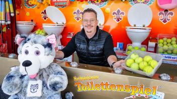 Pfingstmarkt im Rostocker Stadthafen: rund ging es schon am Freitag und (hier) am Sonnabend zwischen Fahrgeschäften und Buden mit vielfältigen Leckereien.Glückliche kleine Besucher wie Cecilia aus Sanitz (4 Jahre jung, das Beste am Pfingstmarkt waren für sie   „die Karussels und Zuckerwatte”) oder der bei „Schultzes Toilettenspiel” treffsichere Kevin (8 Jahre, aus Dettmannsdorf) bevölkerten mit Eltern und Großeltern den Stadthafen.Schausteller wie Rainer Taube zeigten sich zufrieden mit dem Besuch und besonders mit dem „Super Wetter”.Nicht zu warm, kein Regen, nur minimal zu windig. Taube sieht den Sonntag und den Pfingstmontag als die traditionell umsatzstärksten Markttage.Glücklich über das perfekte Pfingst-Wetter war auch Andreas Schultze aus Berlin, der mit seinem „Schultzes Toilettenspiel” regelmäßig in Rostock Station macht.Foto: Georg Scharnweber