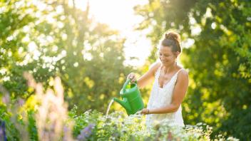 Young woman watering flowers in springtime garden model released Symbolfoto property released AKLF00107