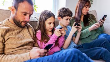 Family using smart phone on sofa at home model released, Symbolfoto property released, WPEF07258