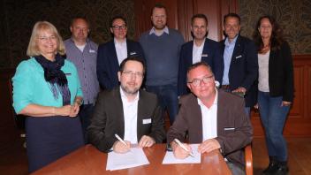 Michael Patt (vorne links), Vorsitzender Wirtschaftsgemeinschaft Pinneberg, und Thilo Binné (vorne rechts), Vorstandsvorsitzender Stadtmarketing Pinneberg, unterzeichneten in Anwesenheit der Vorstandsmitglieder. 