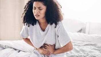 Abdomen pain, period and black woman in bed with abdominal cramps, menstruation and stomach ache. Health, medical emerge