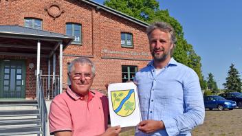 Bürgermeister Jan Kessel und sein Vize Norbert Täufer (l.) präsentieren das neue Wappen der Gemeinde Hohen Pritz. Bald soll es an vielen Stellen in der Kommune zu sehen sein. 