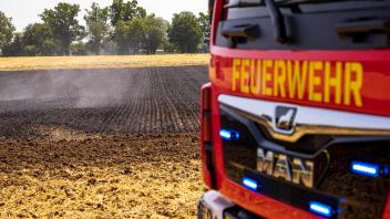 Ein Feuerwehrauto steht vor einem abgebrannten Feld. Flächenbrand auf einem Feld, Themenbild, Symbolbild, 19.07.22 Lens