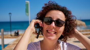 Close-up  of  a  woman  talking  on  the  mobile  phone  on  the  Mediterranean  coast Model Release