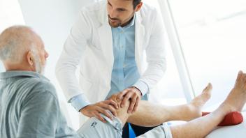 Senior man having his knee examined by a doctor.