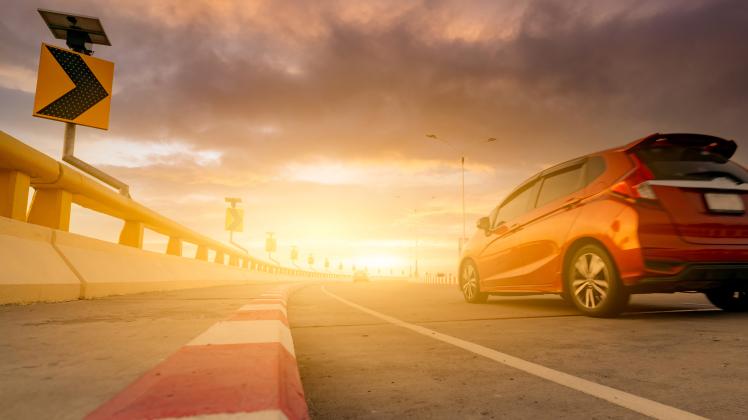 Motion blur of red car driving on curve concrete road with a traffic sign. Road trip on summer vacation. Car drive on th