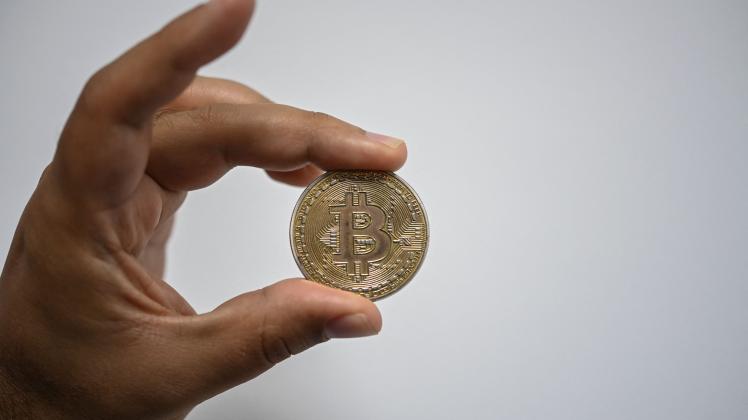 (FILES) A man shows a souvenir coin depicting a bitcoin in Caracas on September 17, 2021. The world of cryptocurrencies in Venezuela, very active due to the search for refuge from inflation and the low cost of electricity, has been shaken by an earthquake of corruption that includes operations with crypto assets linked to the oil industry. (Photo by Yuri CORTEZ / AFP)