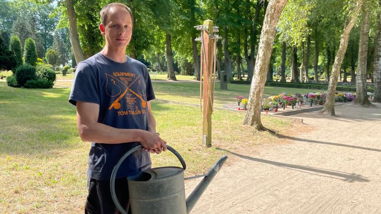 Friedhofmitarbeiter Andy Schmidt hält eine der wenig Gießkannen in den Händen, die auf dem Bützower Friedhof noch bereitstehen. Viele wurden in den zurückliegenden Monaten gestohlen.