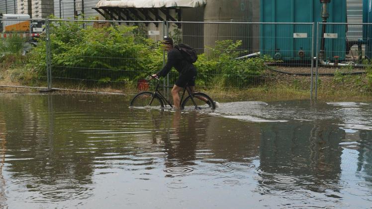 Ein Radfahrer kurbelt sich durch die Wassermassen in Hamburg-Bahrenfeld.